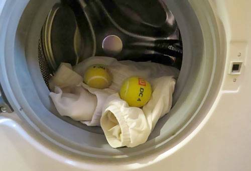 Lavar una chaqueta de plumas en una máquina con bolas.