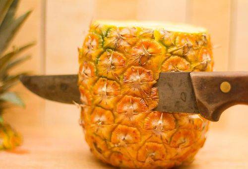 Eine Ananas mit einem Messer schälen