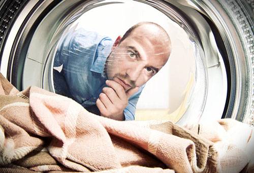 Mees vaatab pesumasinas pesemist