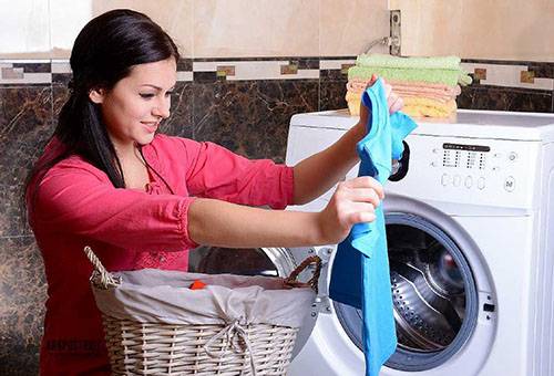 Naine võtab pesumasinast riideid välja