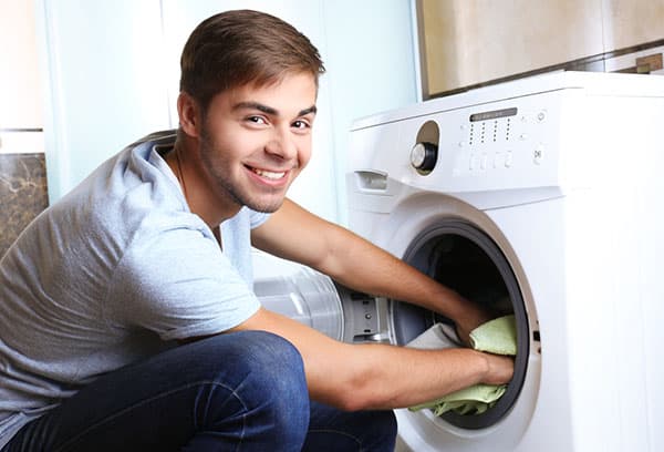 Mees võtab pesumasinast pesu välja