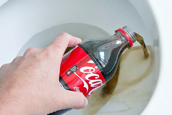 Un hombre vierte Coca-Cola en el baño.