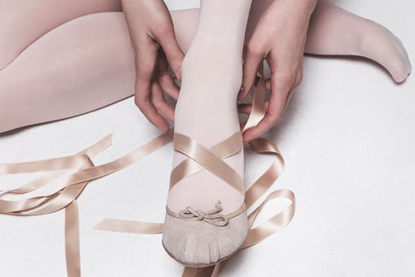 Chica se pone zapatillas de ballet para bailar