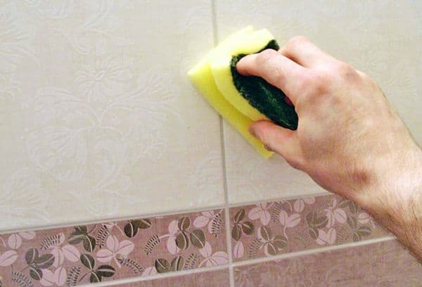 Lavar azulejos con una esponja.