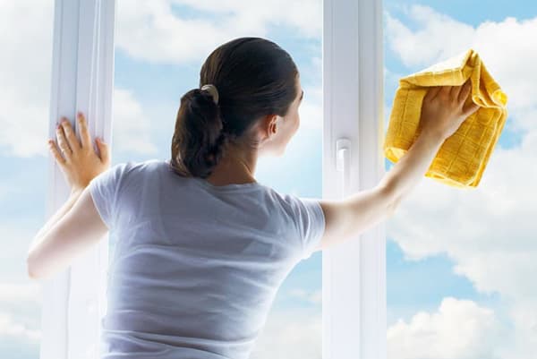Naine peseb päikeselise ilmaga akent