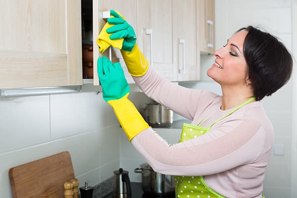 Mujer lavando manijas de gabinetes de cocina