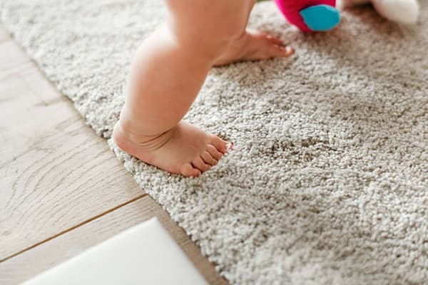 Un niño camina sobre la alfombra.
