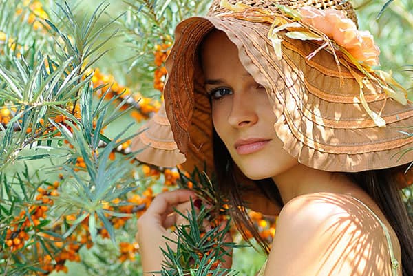 Chica con sombrero cerca de un arbusto de espino amarillo 