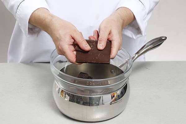 Confectioner melts chocolate in a water bath