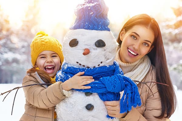 Mamá e hija hacen un muñeco de nieve.