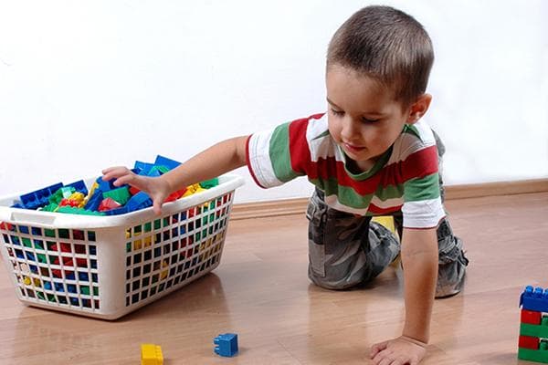 Un niño recoge piezas de un kit de construcción en una cesta