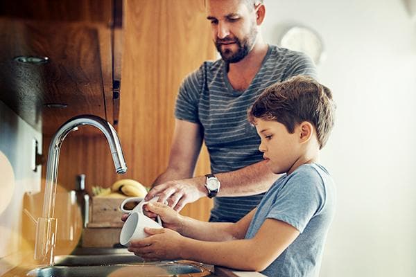 Papá enseña a su hijo a lavar los platos