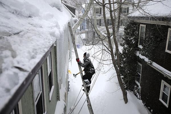 Mees ronib redelit mööda lumisele katusele