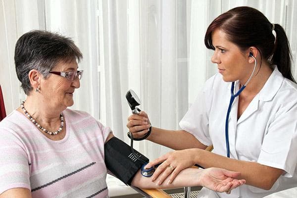 Médico midiendo la presión arterial de un paciente anciano