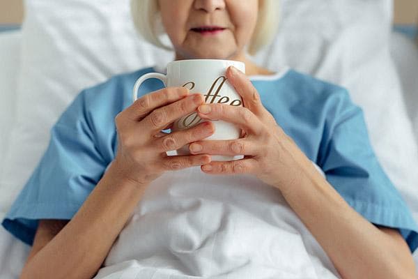 Anciana en la cama tomando café