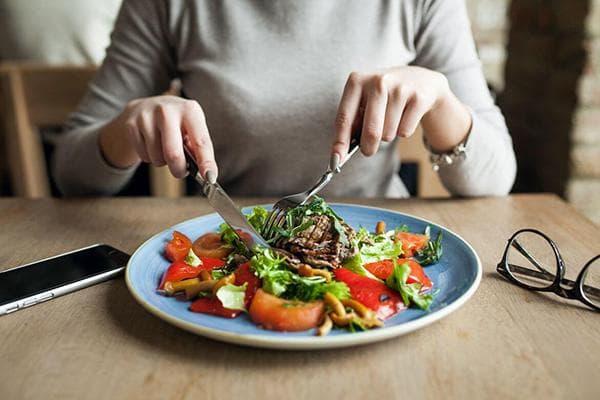 Mujer comiendo carne y ensalada