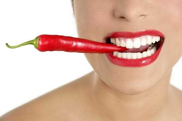 Mujer con pimiento picante en los dientes