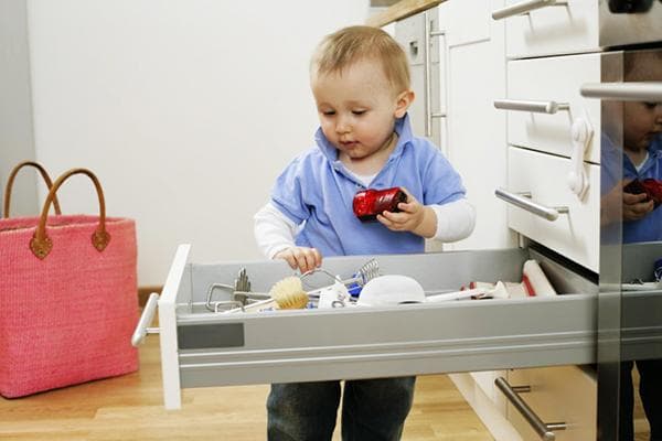 Un niño juega con el contenido de un cajón de la cocina
