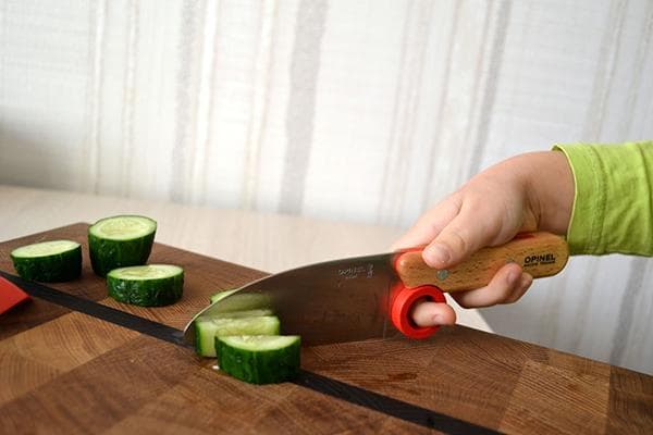 Niño cortando verduras con un cuchillo.