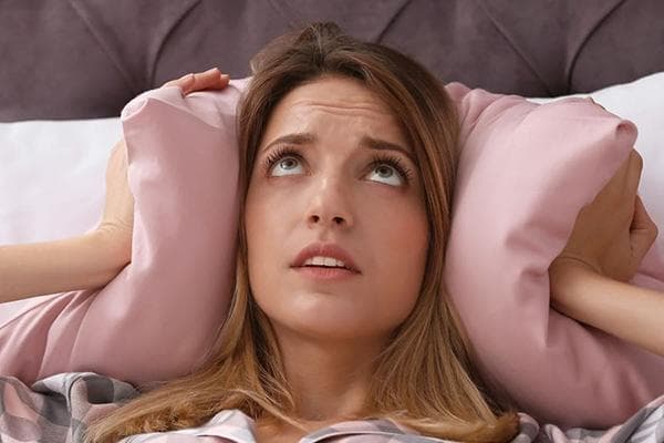 Mujer tapándose los oídos con una almohada