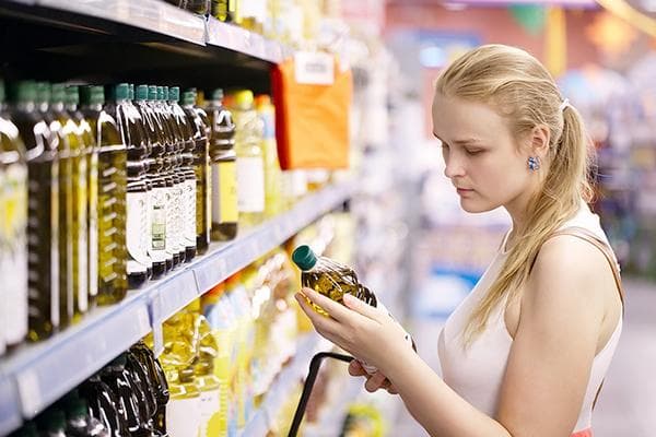 Una niña elige aceite en una tienda.