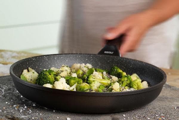 Verduras en una sartén recubiertas con virutas de piedra