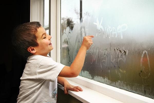 Un niño escribe en una ventana empañada