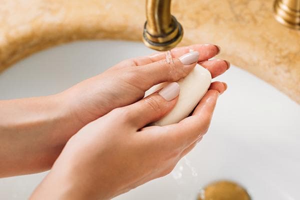 Mujer lavándose las manos con jabón de tocador