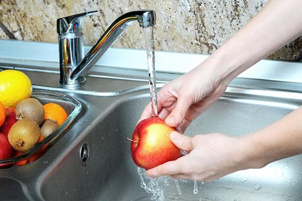 Lavar una manzana con agua corriente.