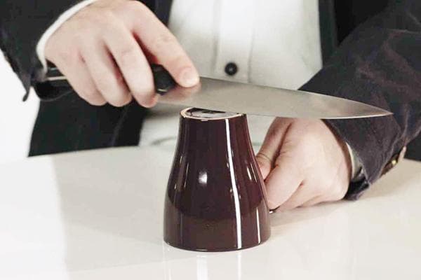 Afilar un cuchillo con una taza de cerámica.