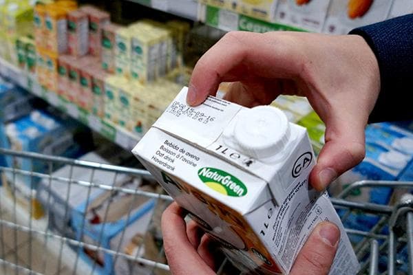 Comprobar la fecha de caducidad de la leche vegetal en la tienda.