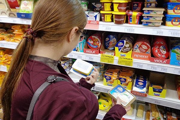 Mujer eligiendo queso procesado en un supermercado