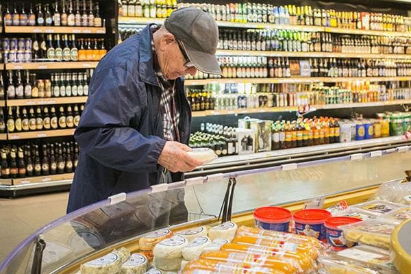 Un hombre elige queso en un hipermercado. 