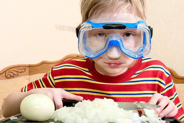 Niño cortando cebollas con gafas de natación