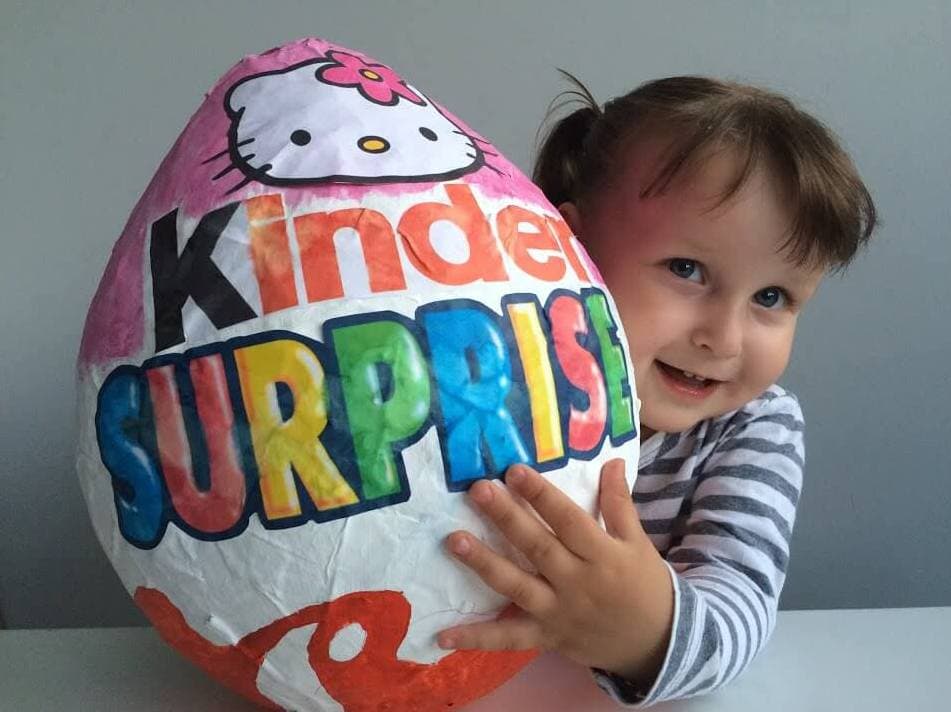 Niño con una sorpresa Kinder gigante de papel maché
