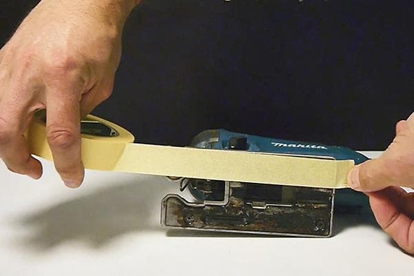 Applying masking tape to the sole of a jigsaw