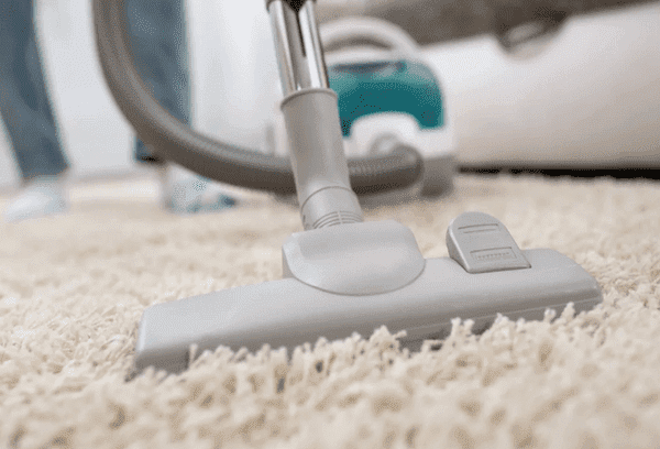 Limpiar la alfombra con una aspiradora.