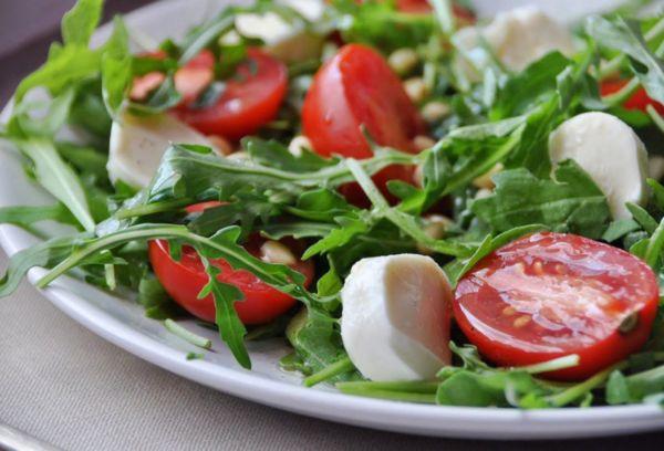 Salad dengan mozzarella dan tomato dan arugula